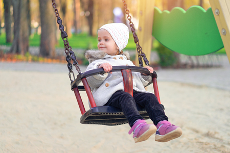 Happy child girl on swing in sunset fall. Little kid playing in the autumn on the nature park Adorable girl having fun on a swing on beautiful autumn dayの写真素材