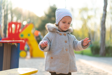 little cute girl playing at the playground in autumn Dressed in the gray fashionable coatの写真素材
