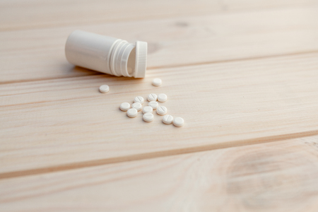 Pills and pill bottle on white wooden background Health care medicine mock up conceptの写真素材