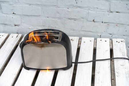Burning toaster. Toaster with two slices of toast caught on fire over white background.の写真素材
