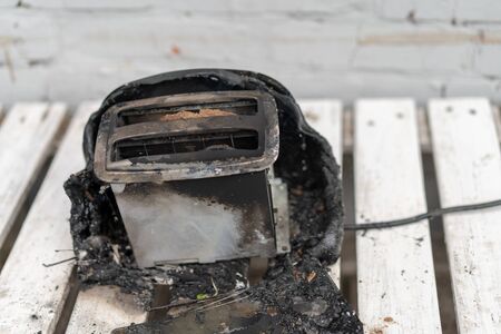 Burning toaster. Toaster with two slices of toast caught on fire over white background. Danger of careless handling of electrical appliances.の写真素材
