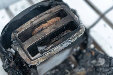 Burning toaster. Toaster with two slices of toast caught on fire over white background. Danger of...