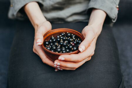 Berries of black currant in plates in female hands. Vitamins and healthy eating concept.の写真素材