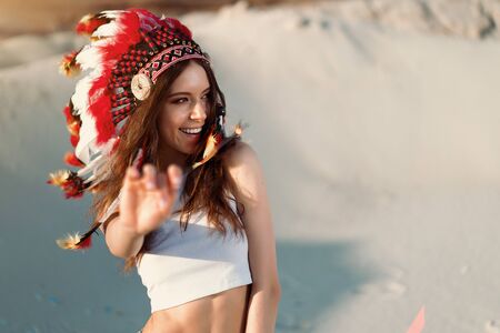 A beautiful young Caucasian girl in a white top on her head is wearing an Indian hat Roach Standing...
