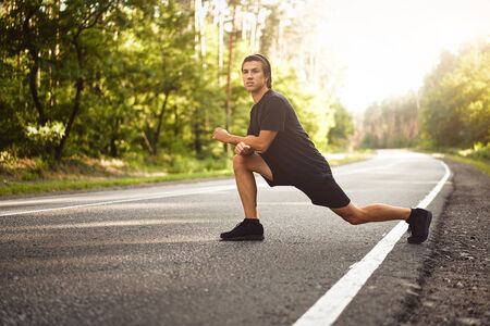 Middle age man warming up at forest road before jogging. Men stretching for running exercises. Handsome 30s athlet doing fitness outdoor at summer day. Healthy lifestyle conceptの写真素材