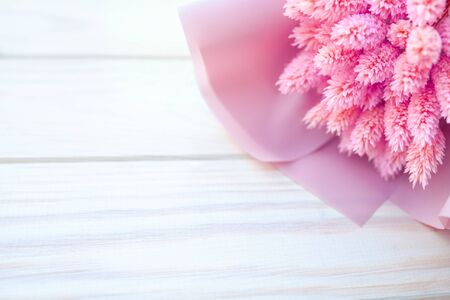 Beautiful bouquet of dry pink flowers on a wooden white background. Minimalism, space for text. Gift Card. abstract spring theme.の写真素材