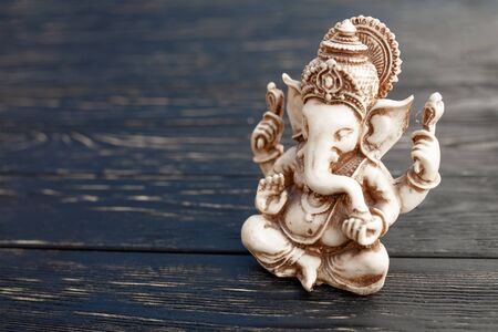 Hindu god Ganesh on black wooden background. Statue on table close up with copy space for textの写真素材