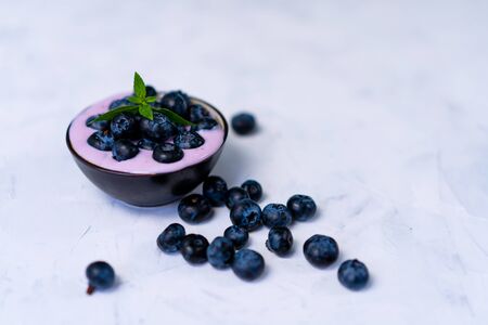 Tasty fresh blueberry yoghurt shake dessert in ceramic bowl standing on white table background. Homemade berry smoothie. Healthy eating. Diet food.の写真素材