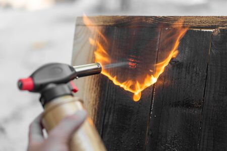 Professional carpenter using old traditional japanese technique. Burning wood planks with gas...