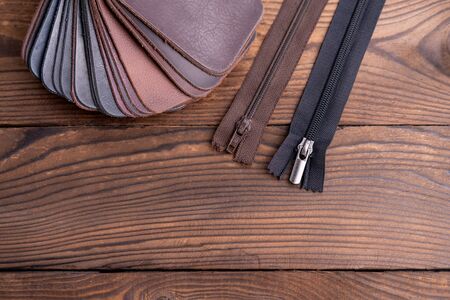 Leather samples for shoes and zipper  on dark wooden table. Designer furniture clothes.の写真素材