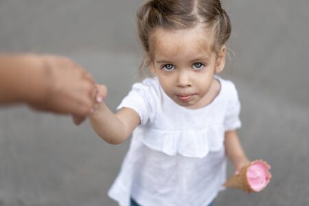 Little caucasian girl 3 years old eats ice cream closeup portrait. Summertime. Childhood  Child with...