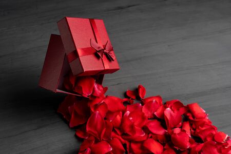 Beautiful red roses next to a gift red box on a dark cement background. New Year birthday Valentine's Day Mother's Day presentの写真素材