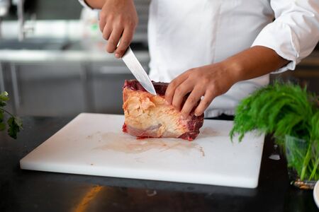 unrecognizable young African chef standing in professional kitchen in restaurant preparing a meal of...