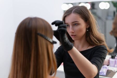 Young beautician caucasian girl holds model eyebrow correction Beautician at work is the workplace of an eyebrow specialist. Eyebrow correction and dyeing procedure. Beauty industry. Lifestyleの写真素材