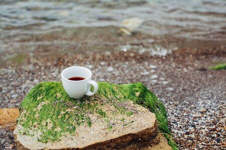 cup of coffee on the sea water and stone background. Sea freshness morning concept.の写真素材