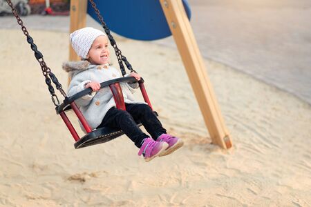 Happy child girl on swing in sunset fall. Little kid playing in the autumn on the nature park Adorable girl having fun on a swing on beautiful autumn dayの写真素材