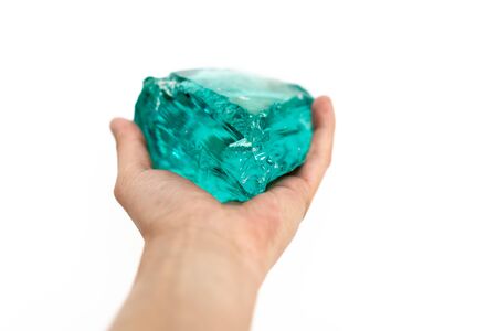 Large artificial semi-precious emerald stone in human hand isolated on the white backgroundの写真素材