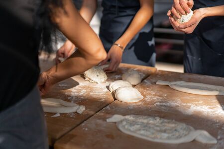 Culinary master class. Closeup of people hands preparing khachapuri. Traditional georgian cheese bread. Georgian food. Big unrecognizable family cooking hands close upの写真素材