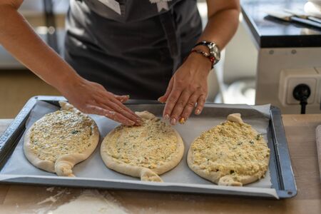 Culinary master class. Closeup of people hands preparing khachapuri. Traditional georgian cheese bread. Georgian food. Big unrecognizable family cooking hands close upの写真素材