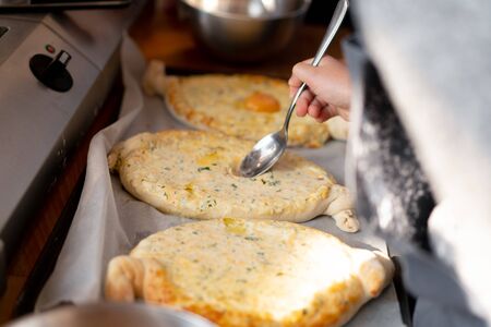 Culinary master class. Closeup of people hands preparing khachapuri. Traditional georgian cheese bread. Georgian food. Big unrecognizable family cooking hands close upの写真素材