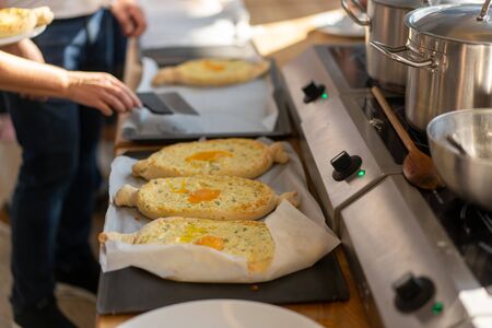 Culinary master class. Closeup of people hands preparing khachapuri. Traditional georgian cheese bread. Georgian food. Big unrecognizable family cooking hands close upの写真素材