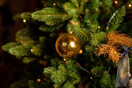 Close-up of a Christmas tree decorated with gold balls and blue bows. Christmas holiday concept. Free space for textの写真素材