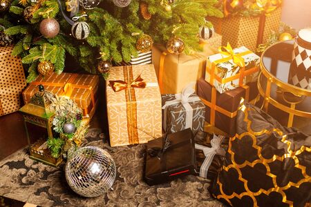 Close-up of a Christmas tree decorated with gold balls. Under the Christmas tree a large number of Christmas gifts. Christmas holiday concept. A huge number of gift boxes under Holiday backgroundの写真素材