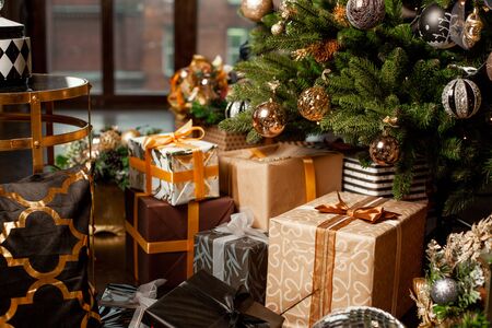 Close-up of a Christmas tree decorated with gold balls. Under the Christmas tree a large number of Christmas gifts. Christmas holiday concept. A huge number of gift boxes under Holiday backgroundの写真素材
