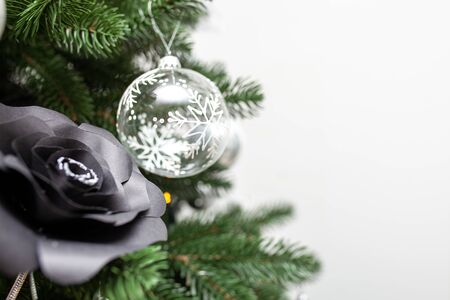 Close-up of a Christmas tree decorated with transparent balls and black paper roses. Christmas holiday concept.の写真素材