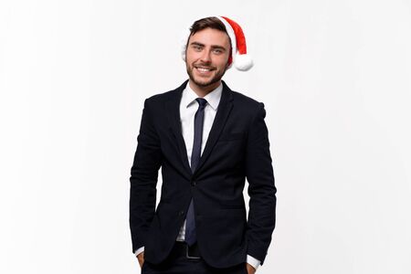 Young handsome caucasian guy in business suit and Santa hats stands on white background in studio teeth smilie. Close up portrait business person with Christmas mood Holiday bannerの写真素材