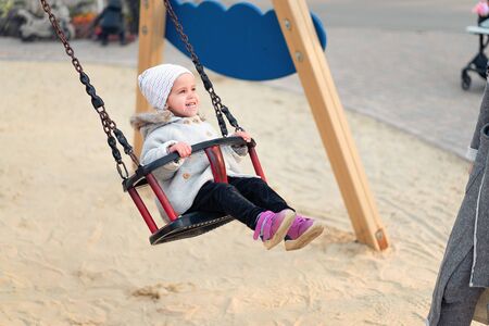 Happy child girl on swing in sunset fall. Little kid playing in the autumn on the nature park Adorable girl having fun on a swing on beautiful autumn dayの写真素材