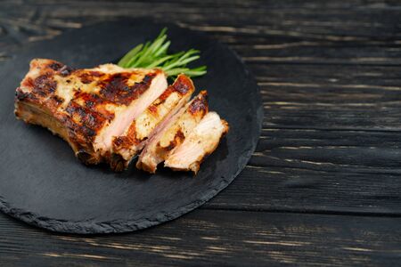 A juicy piece of fried meat lies on a stone plate against a black wooden table. Degree of roasting well done. Food concept with copy spaceの写真素材