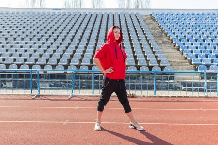 Portrait of a beautiful Caucasian girl athlete on a summer morning jog. A woman is wearing a red fashionable hoodie hoodie. Summer Sport Fitness Healthy Lifestyleの写真素材