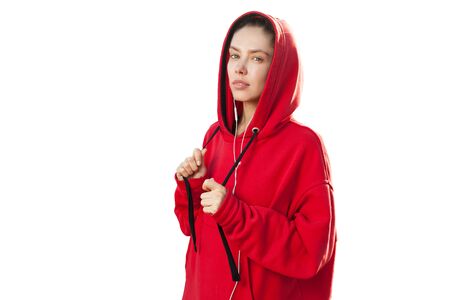 Beautiful caucasian sporty woman to trendy red hoodie on white background in studioの写真素材