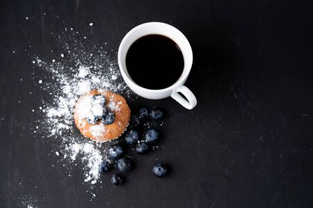 Blueberry antioxidant organic superfood and sweet muffin with cup of coffe Concept for healthy eating and dieting nutrition Top view on dark black backgroundの写真素材
