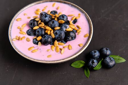 Tasty fresh blueberry yoghurt shake dessert in ceramic bowl standing on black table background. Homemade berry smoothie. Healthy eating. Diet food. yogurtの写真素材