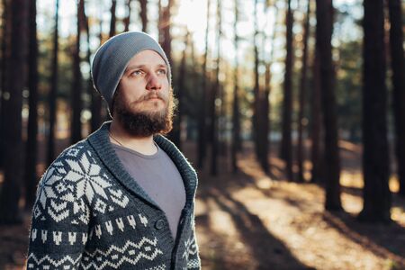a young man with a beard walks in a pine forest. Portrait of a brutal bearded man Autumn forest tourism conceptの写真素材