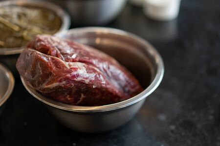 A large juicy piece of beef meat lies in a metal plate on a table against a dark background.の写真素材