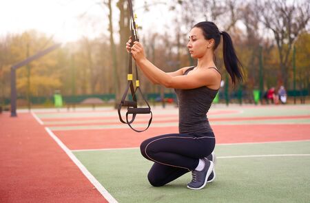 Girl athlete functional training sportground Mixed race young adult woman workout  suspension system Healthy lifestyle Stretching outdoors playground Make your body machine                            の写真素材