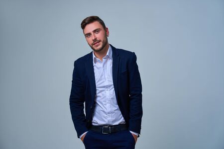 Close up portrait young man businessman. Caucasian guy business suit studio gray background. Modern business person stylish haircut earring in ear. Portrait of charming successful young entrepreneurの写真素材