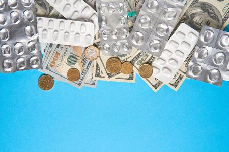 pills empty blisters for drugs individual syringe and money lie on a blue background Expensive medicine health insurance concept. Expensive treatment of diseases. Budget for medical expenses.の写真素材