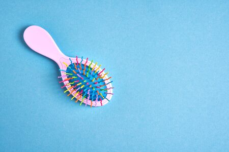 Funny baby comb with multi-colored plastic wavy bristles lies on a blue background. with free space for textの写真素材