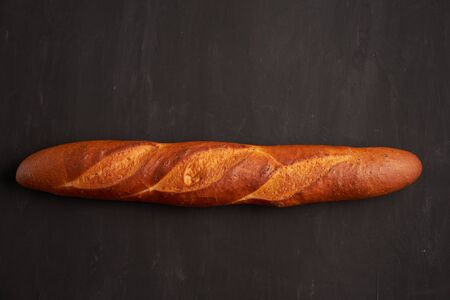 one crispy french baguettes lie dark black table background sesame seeds Classic french national pastries Copy space Concept for menu or advertisingの写真素材