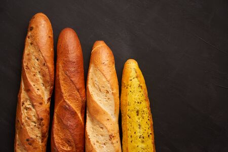 Three crispy french baguettes lie dark black table background sesame seeds Classic french national pastries Copy space Concept for menu or advertisingの写真素材