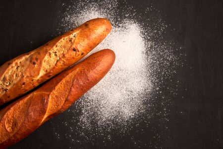 Two crispy french baguettes lie dark black table background sesame seeds Classic french national pastries Copy space Concept for menu or advertisingの写真素材