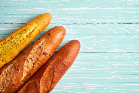 Three crispy french baguettes lie blue wooden background baguettes in assortment with sesame seeds...
