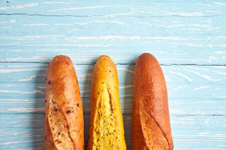 Three crispy french baguettes lie blue wooden background baguettes in assortment with sesame seeds...