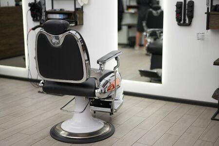 Classic vintage barber chair stands opposite mirror stylish white barber shop interior Man hairdresser salon Empty retro armchair in barbershop Professional hairstylist workplace Nobody Copy spaceの写真素材