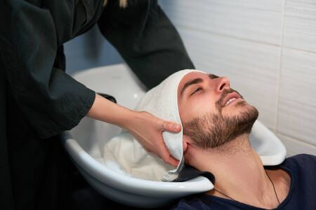 Woman applying shampoo massaging hair customer  Man wash hair in beauty salon Hairdresser washing hair. Happy caucasian guy enjoy service in barbershop Preparing the client before hairdressingの写真素材