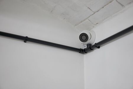 White round cctv camera installed in the corner on a white wall. Minimalism. Corner.の写真素材